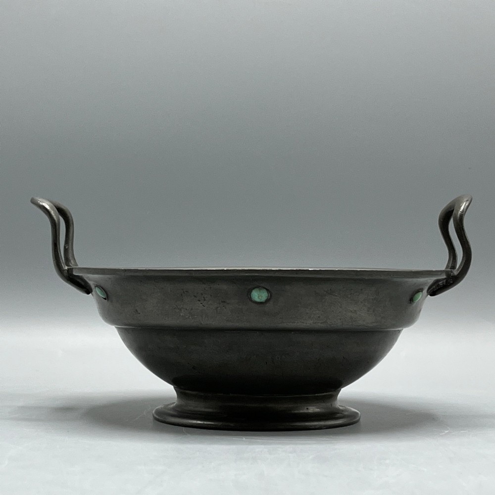 An Arts and Crafts pewter porringer bowl featuring twin raised handles, a pedestal base, and small turquoise cabochons set into the exterior rim. View VII