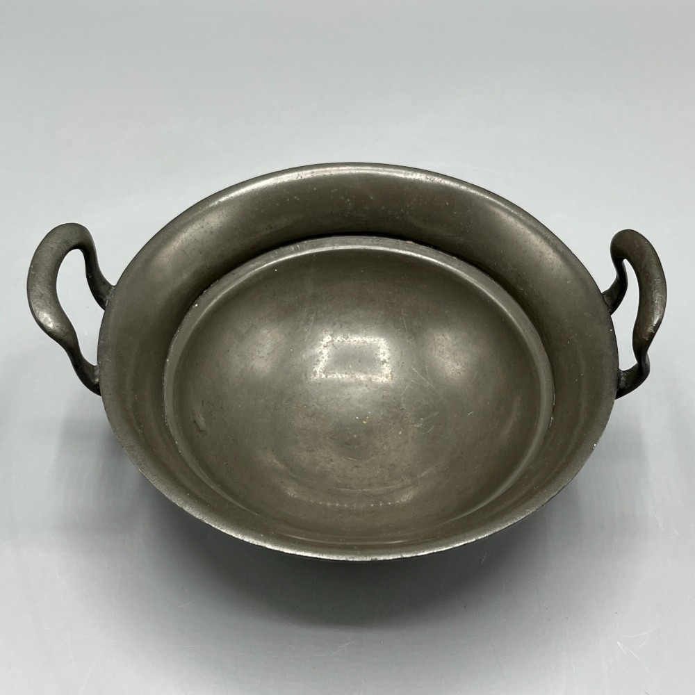 An Arts and Crafts pewter porringer bowl featuring twin raised handles, a pedestal base, and small turquoise cabochons set into the exterior rim. View X
