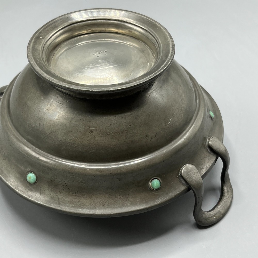 An Arts and Crafts pewter porringer bowl featuring twin raised handles, a pedestal base, and small turquoise cabochons set into the exterior rim. View XIV