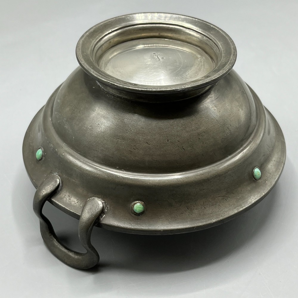 An Arts and Crafts pewter porringer bowl featuring twin raised handles, a pedestal base, and small turquoise cabochons set into the exterior rim. View XV