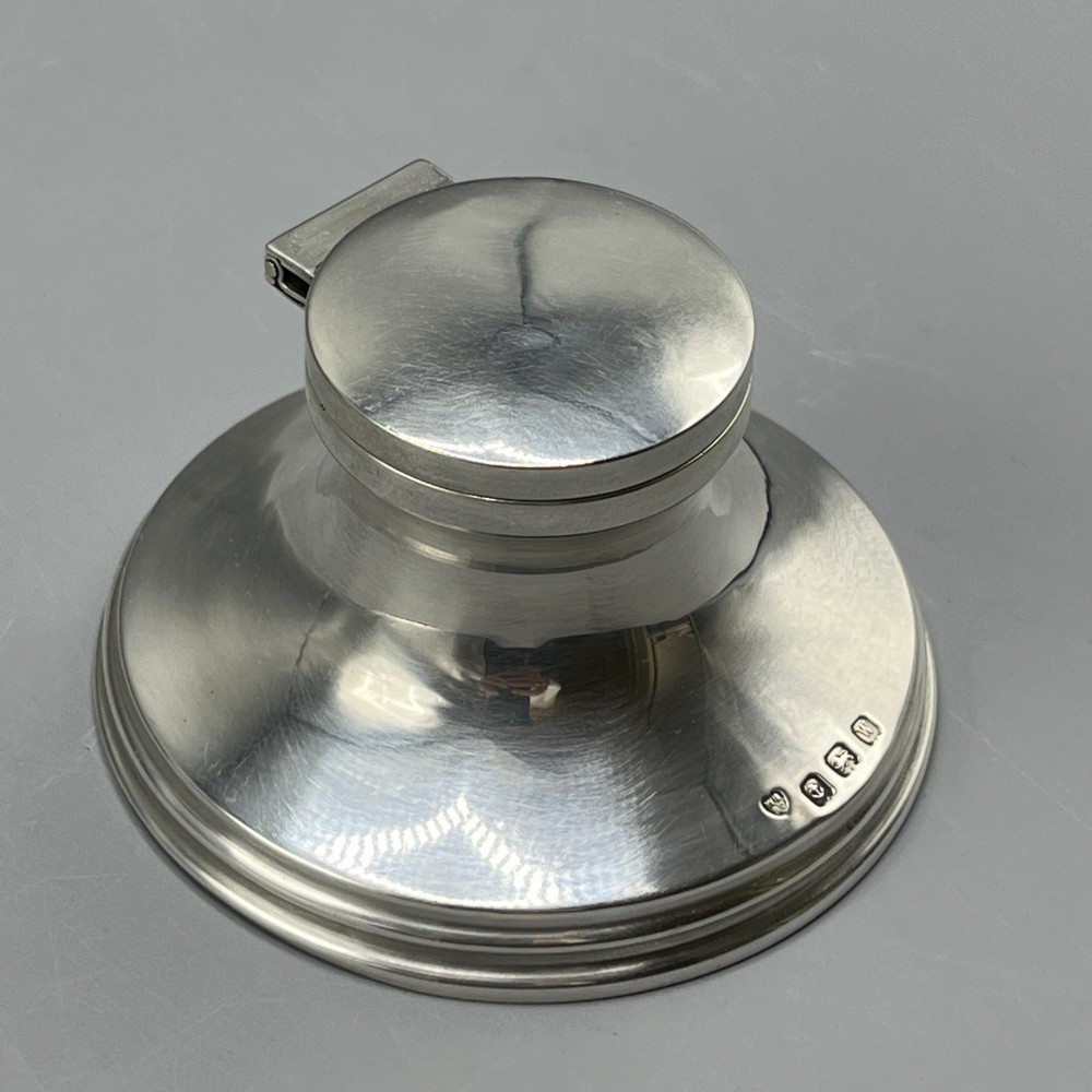 An Art Deco sterling silver capstan inkwell featuring a smooth hinged lid, circular stepped base, and visible hallmarks. View III
