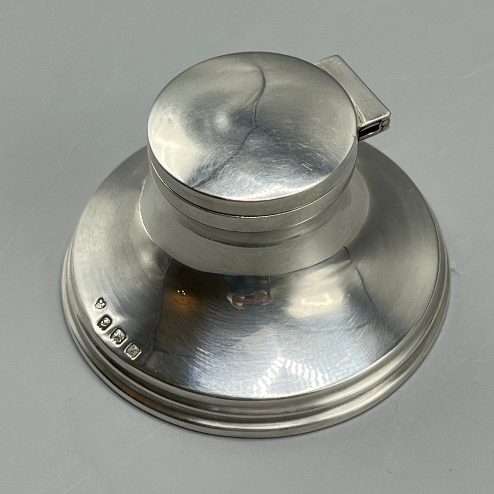 An Art Deco sterling silver capstan inkwell featuring a smooth hinged lid, circular stepped base, and visible hallmarks. View IV