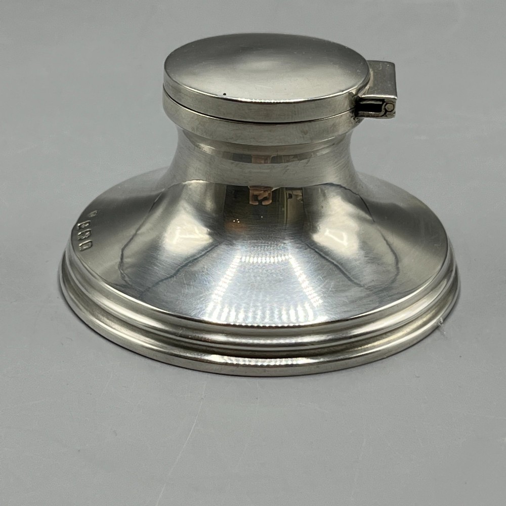 An Art Deco sterling silver capstan inkwell featuring a smooth hinged lid, circular stepped base, and visible hallmarks. View VI