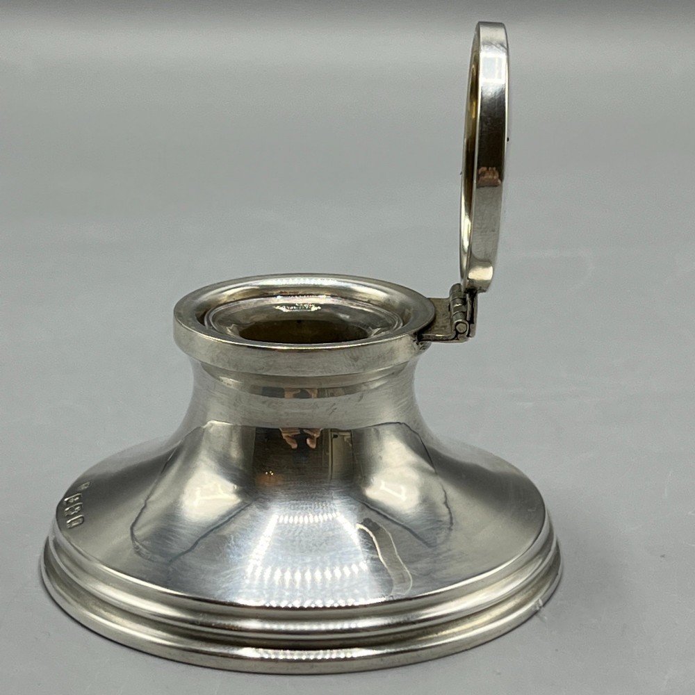 An Art Deco sterling silver capstan inkwell featuring a smooth hinged lid, circular stepped base, and visible hallmarks. View VII