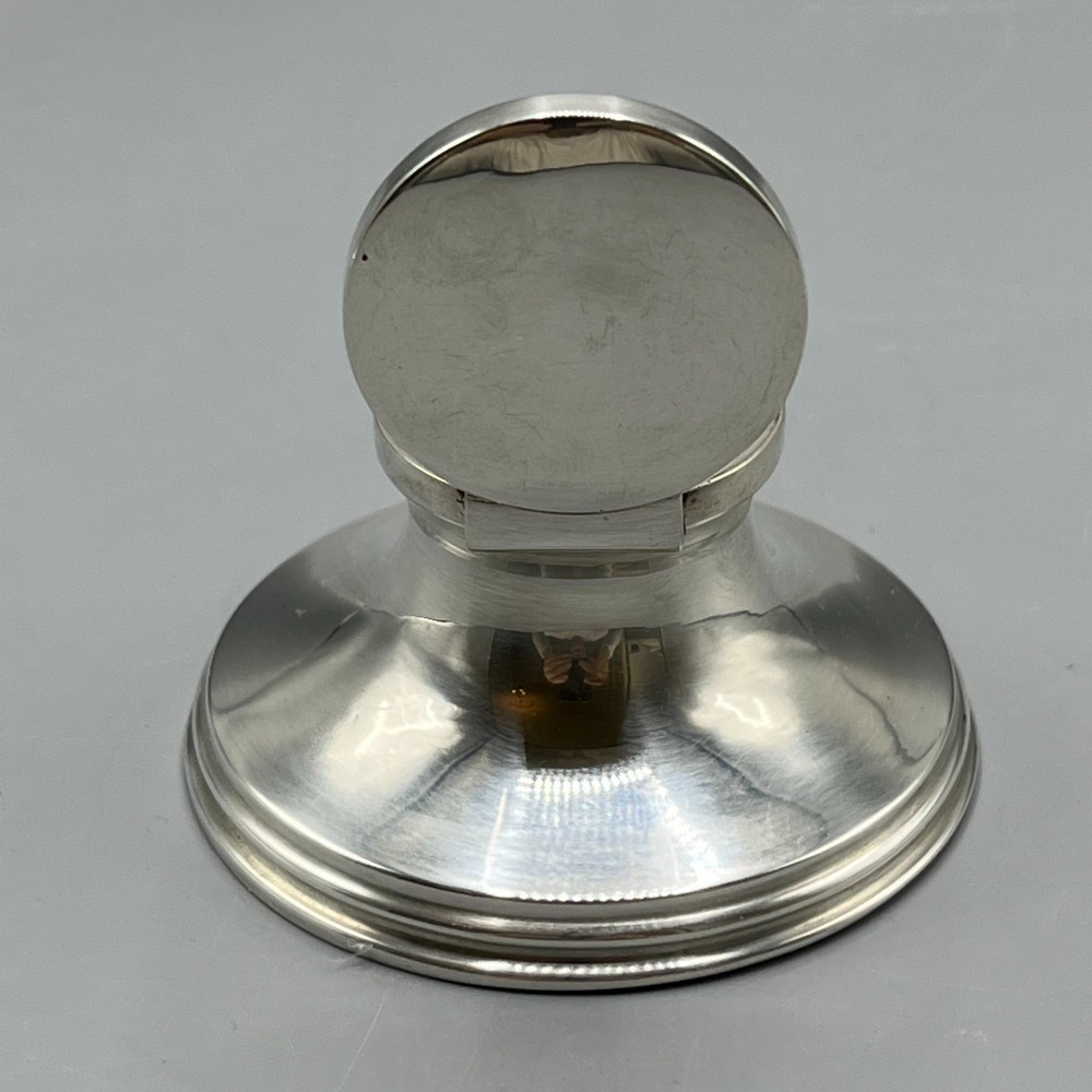 An Art Deco sterling silver capstan inkwell featuring a smooth hinged lid, circular stepped base, and visible hallmarks. View VIII