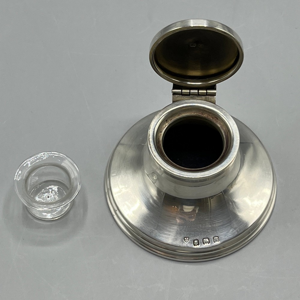 An Art Deco sterling silver capstan inkwell featuring a smooth hinged lid, circular stepped base, and visible hallmarks. View XI