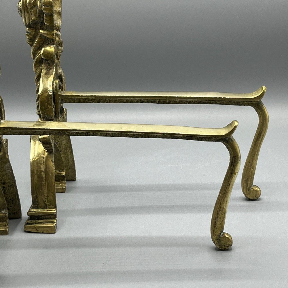A pair of ornate Victorian solid brass fire dogs featuring finials, twisted columns, medallion details, and arched scrolled feet against a grey backdrop. View XIV