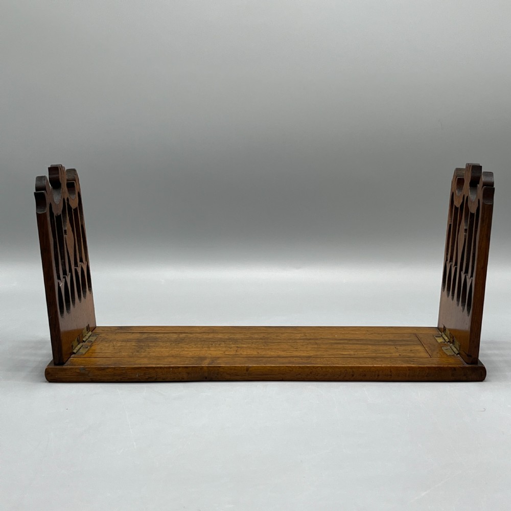 An Edwardian wooden extending book slide featuring carved pierced fretwork ends attached with brass hinges to a smooth base. View III