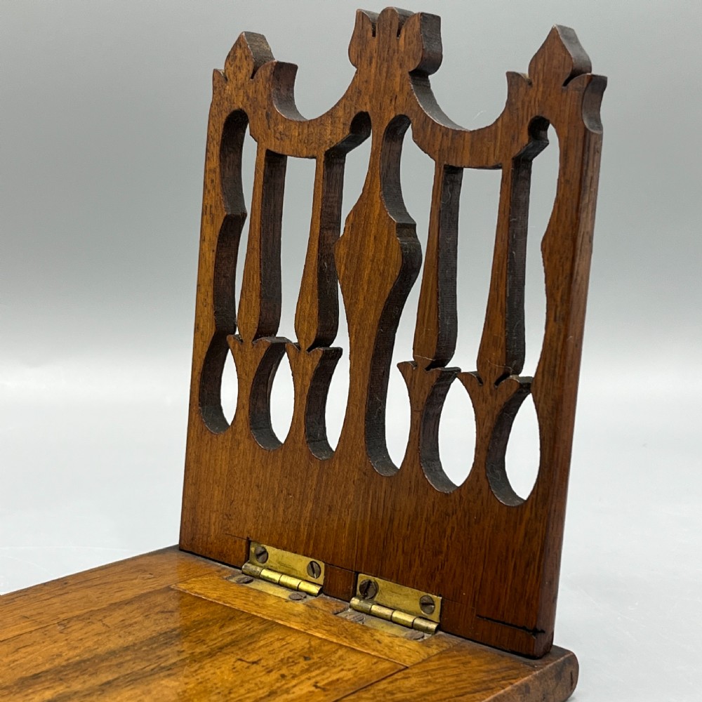 An Edwardian wooden extending book slide featuring carved pierced fretwork ends attached with brass hinges to a smooth base. View IV