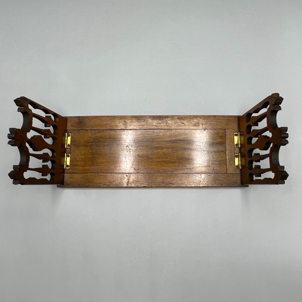 An Edwardian wooden extending book slide featuring carved pierced fretwork ends attached with brass hinges to a smooth base. View VI