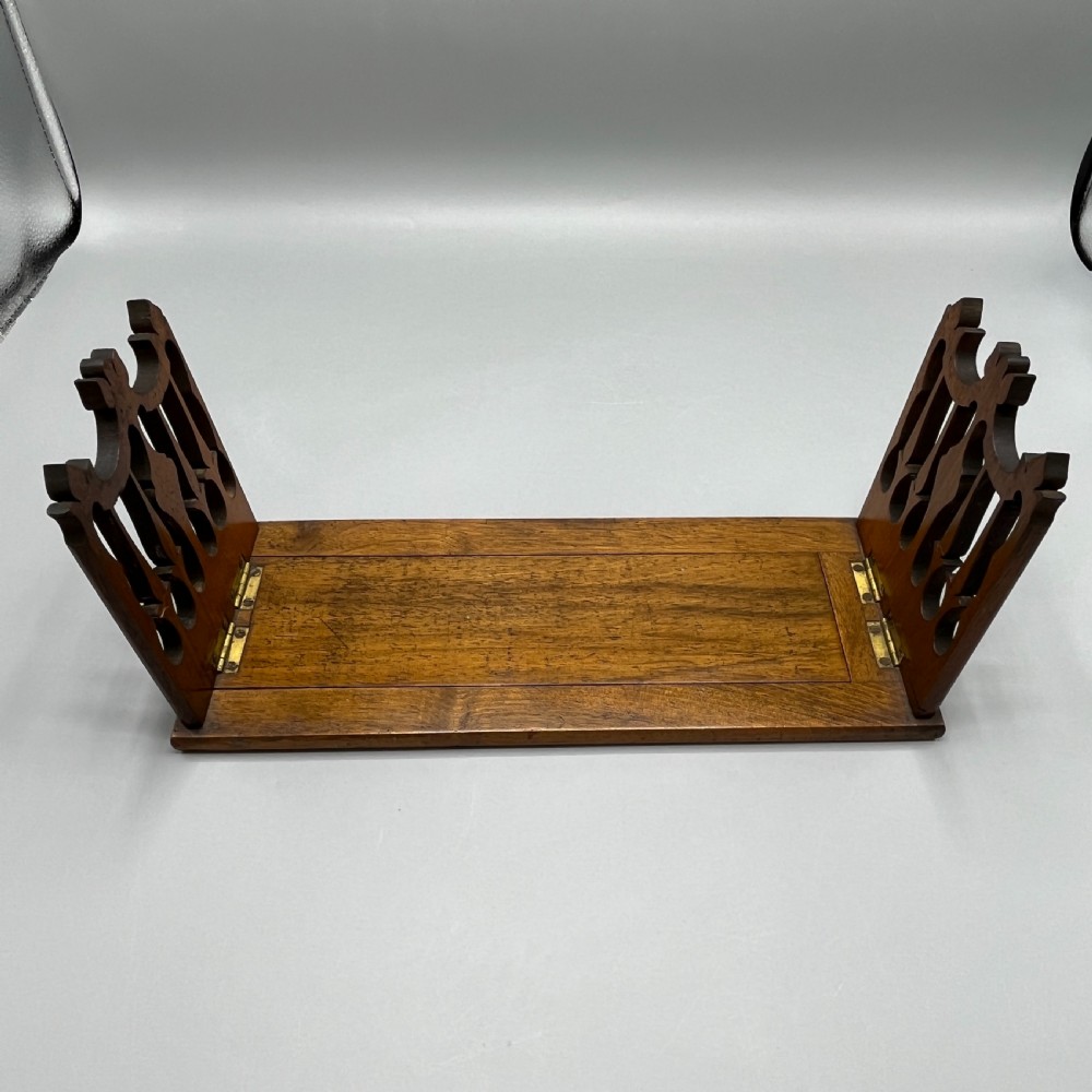 An Edwardian wooden extending book slide featuring carved pierced fretwork ends attached with brass hinges to a smooth base. View VII