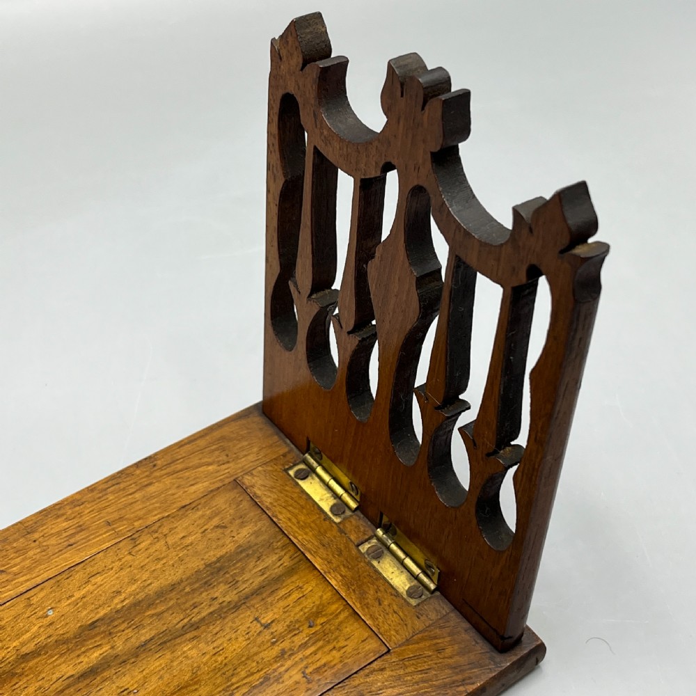 An Edwardian wooden extending book slide featuring carved pierced fretwork ends attached with brass hinges to a smooth base. View IX