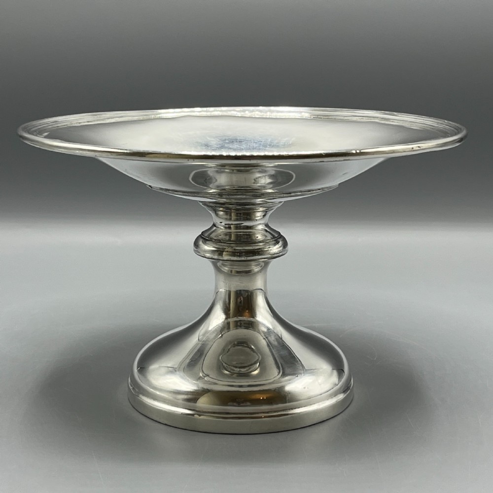 A circular silver-plated tazza dish with a shallow tray resting on a moulded pedestal stem and flared base.