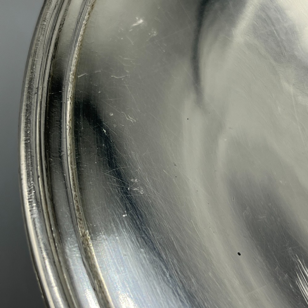 A circular silver-plated tazza dish with a shallow tray resting on a moulded pedestal stem and flared base. View V