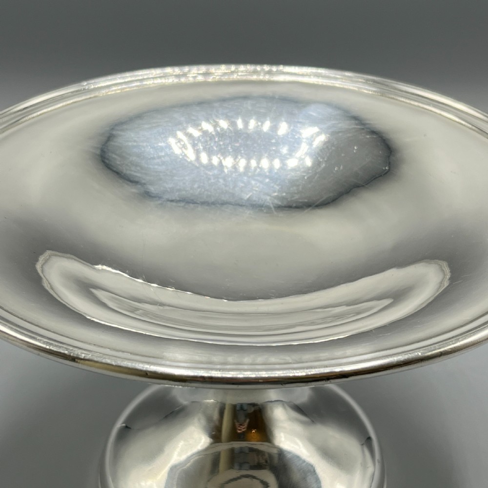 A circular silver-plated tazza dish with a shallow tray resting on a moulded pedestal stem and flared base. View X