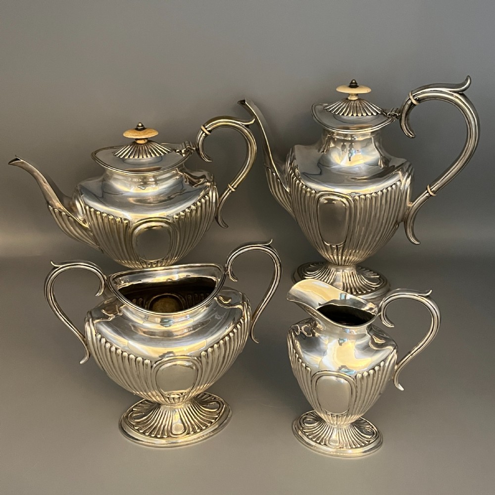 A four-piece Victorian silver-plated tea and coffee set featuring a teapot, coffee pot, sugar bowl, and cream jug with fluted bodies and pedestal bases. View II
