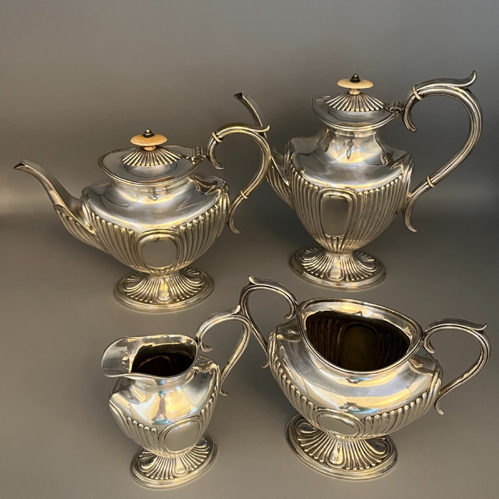 A four-piece Victorian silver-plated tea and coffee set featuring a teapot, coffee pot, sugar bowl, and cream jug with fluted bodies and pedestal bases. View III
