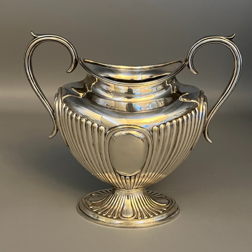 A four-piece Victorian silver-plated tea and coffee set featuring a teapot, coffee pot, sugar bowl, and cream jug with fluted bodies and pedestal bases. View VI