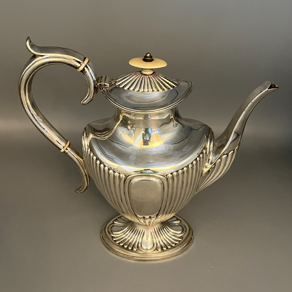 A four-piece Victorian silver-plated tea and coffee set featuring a teapot, coffee pot, sugar bowl, and cream jug with fluted bodies and pedestal bases. View X