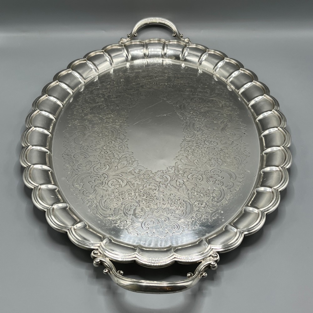 A large oval silver plated serving tray featuring twin scroll handles, a scalloped rim, and chased foliage patterns across the flat interior. View III