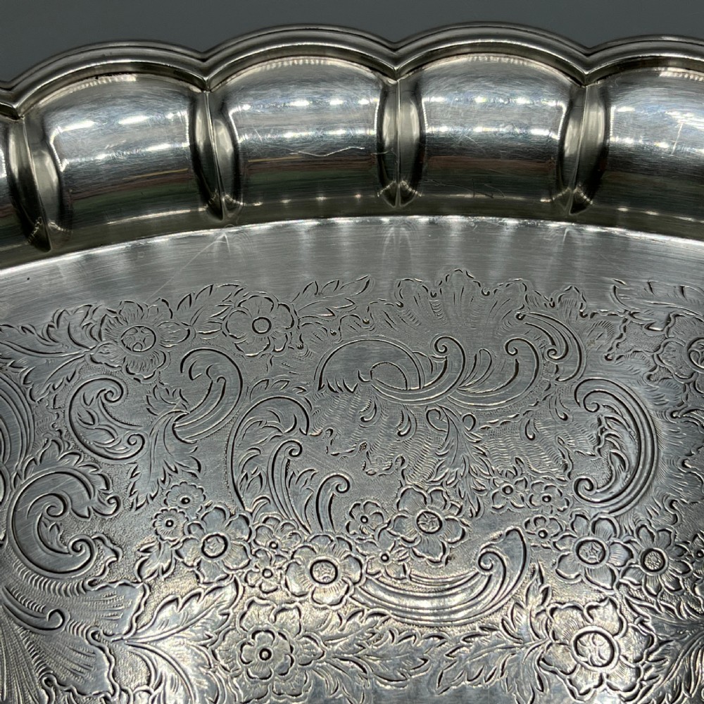 A large oval silver plated serving tray featuring twin scroll handles, a scalloped rim, and chased foliage patterns across the flat interior. View IX