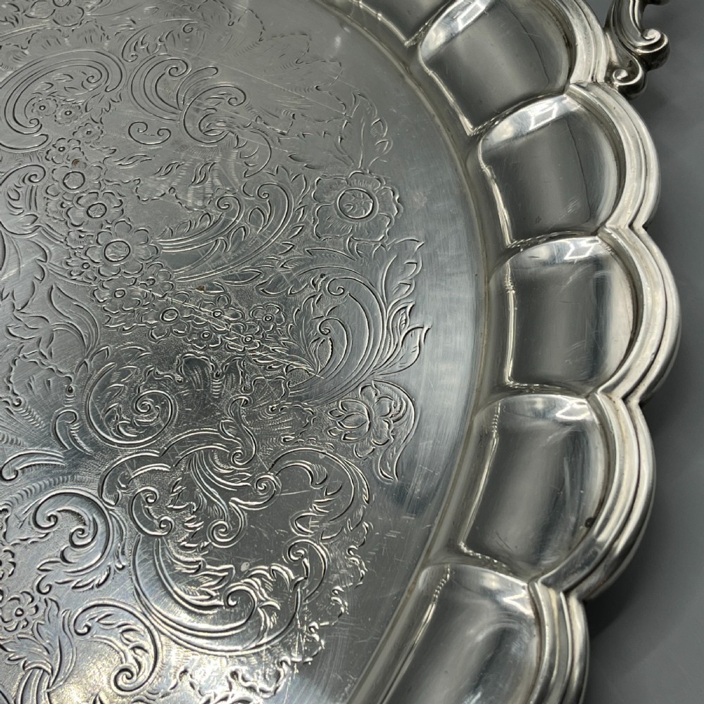 A large oval silver plated serving tray featuring twin scroll handles, a scalloped rim, and chased foliage patterns across the flat interior. View XIII