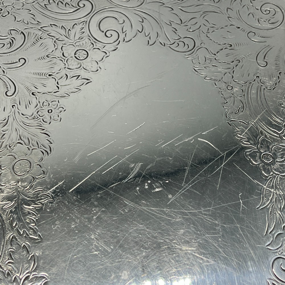 A large oval silver plated serving tray featuring twin scroll handles, a scalloped rim, and chased foliage patterns across the flat interior. View XVII