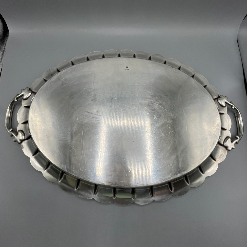 A large oval silver plated serving tray featuring twin scroll handles, a scalloped rim, and chased foliage patterns across the flat interior. View XXI