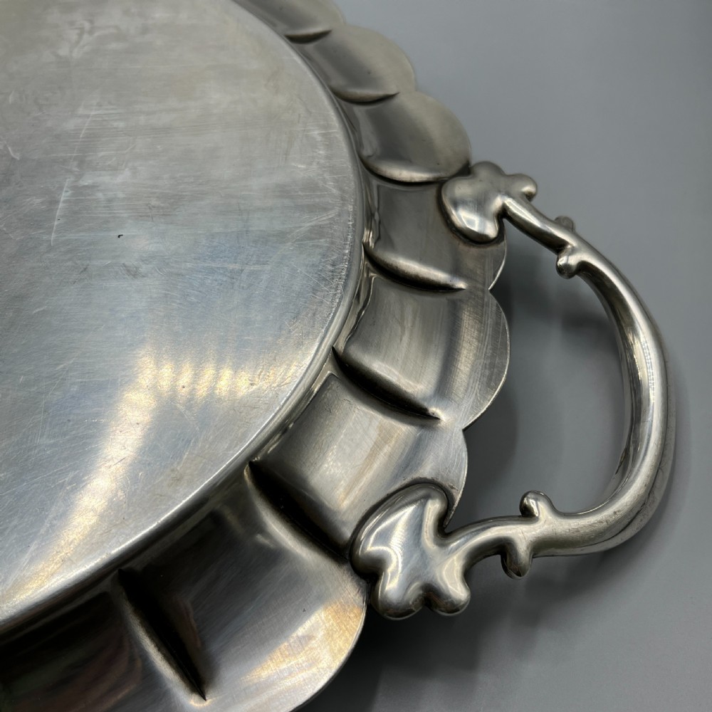 A large oval silver plated serving tray featuring twin scroll handles, a scalloped rim, and chased foliage patterns across the flat interior. View XXII