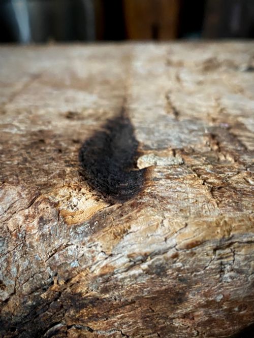 fig 3. A thick section of hand-hewn solid oak timber displaying natural wood grain, fissures, and surface burn markings.