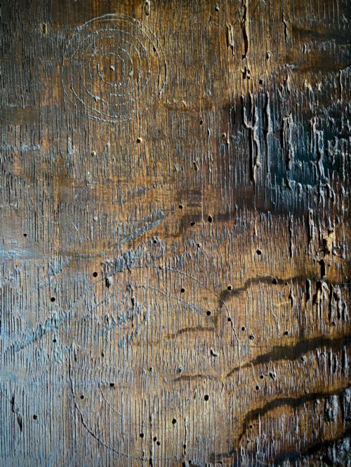 fig 4. A carved dark oak panel featuring a repetitive geometric foliage pattern beside a detailed close-up of incised concentric circles and ritual marks on the wood grain.