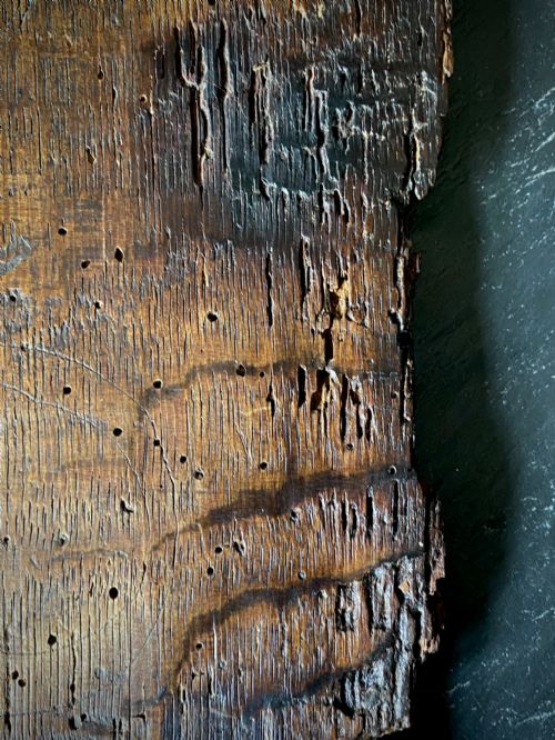 fig 5. A carved dark oak panel featuring a repetitive geometric foliage pattern beside a detailed close-up of incised concentric circles and ritual marks on the wood grain.
