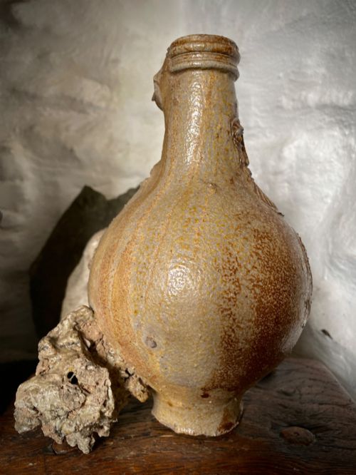 fig 3. A salt-glazed stoneware Bartmann jug featuring a moulded bearded face mask on the neck and a round medallion crest on the globular body.