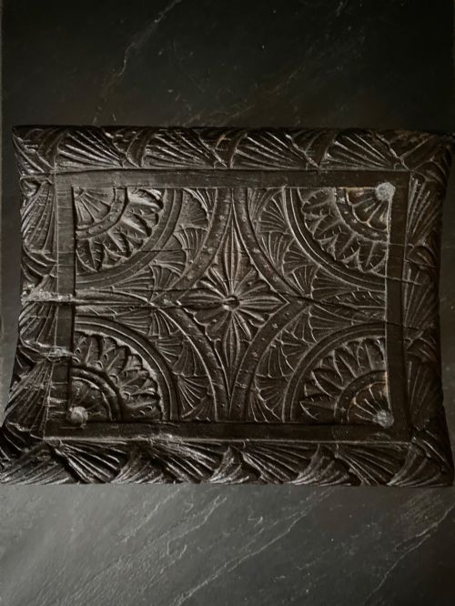 fig 2. A dark brown carved oak stool featuring hand-carved shell motif decoration on the top seat and four turned wooden legs.
