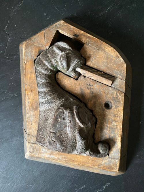 fig 1. A three-piece set of carved wooden pattern moulds featuring a central seated gargoyle figure flanked by two bat-like wing panels with red paint accents.