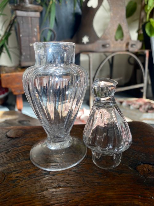 fig 1. An 18th-century clear hand-blown glass dry mustard jar featuring vertical fluting, a circular footed base, and a removable pointed glass stopper.