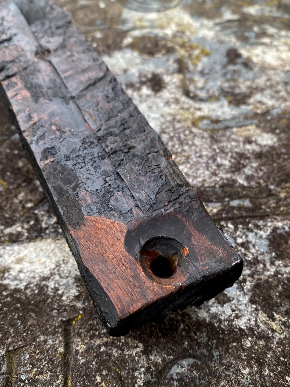 A dark carved oak wooden fragment depicting a stylized human face and decorative geometric relief details. View XI