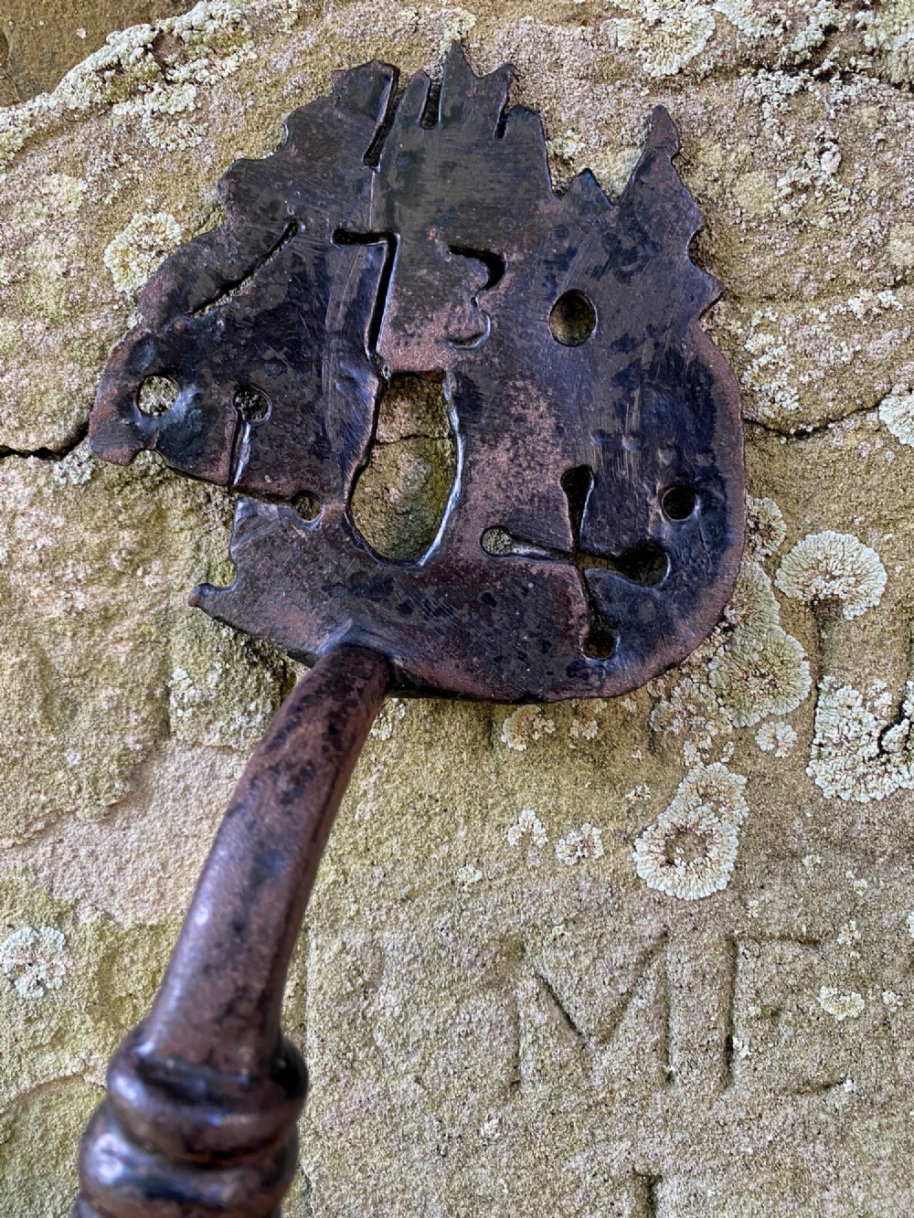 An 18th-century hand-forged wrought iron door handle featuring pierced decorative motifs, stamped initials, and the date 1730. View II