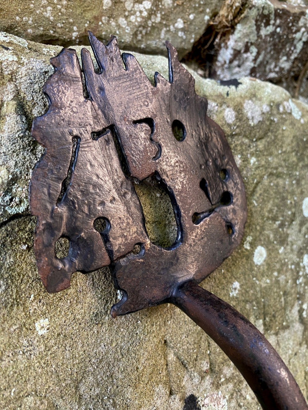 An 18th-century hand-forged wrought iron door handle featuring pierced decorative motifs, stamped initials, and the date 1730. View IV
