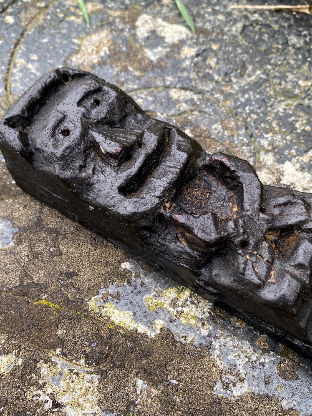 A vertical dark oak wood carving depicting a stylised human face and figure with hand-chiselled detailing. View II