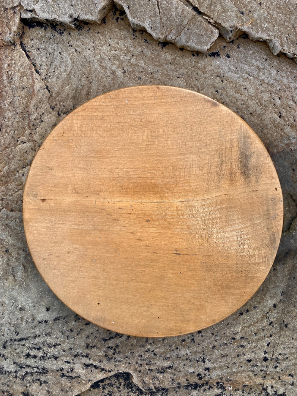 A circular turned sycamore wooden platter featuring a raised rim, shallow basin with knife marks, and a dark triangular iron burn mark in the centre. View VI