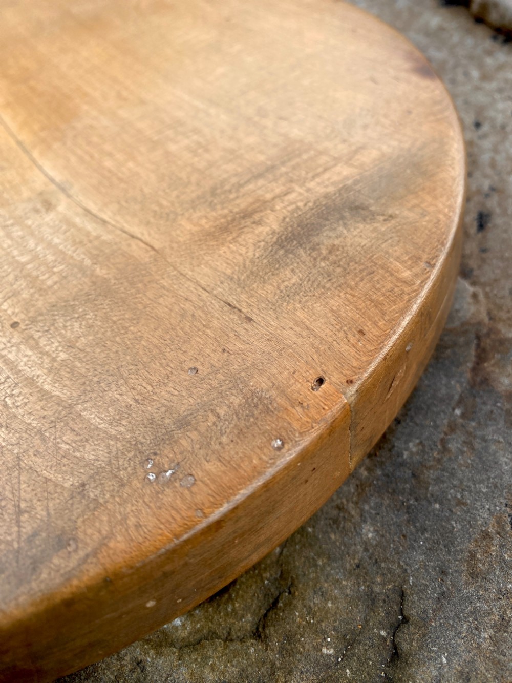 A circular turned sycamore wooden platter featuring a raised rim, shallow basin with knife marks, and a dark triangular iron burn mark in the centre. View VII