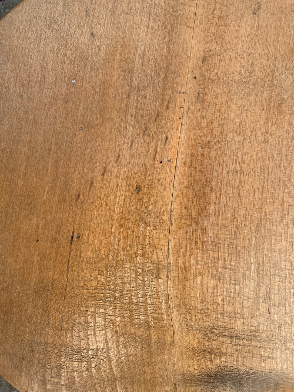 A circular turned sycamore wooden platter featuring a raised rim, shallow basin with knife marks, and a dark triangular iron burn mark in the centre. View IX