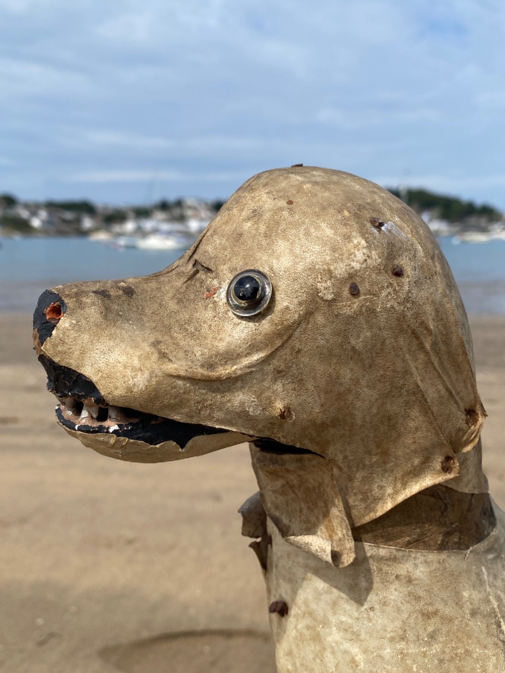 An early twentieth-century folk art dog head sculpture constructed from aged parchment leather with glass eyes and a movable mouth revealing painted teeth. View VII