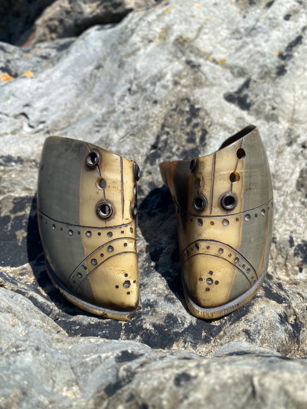 A pair of 19th-century folk art miniature shoes crafted from horn with incised shoe details and punched eyelets.
