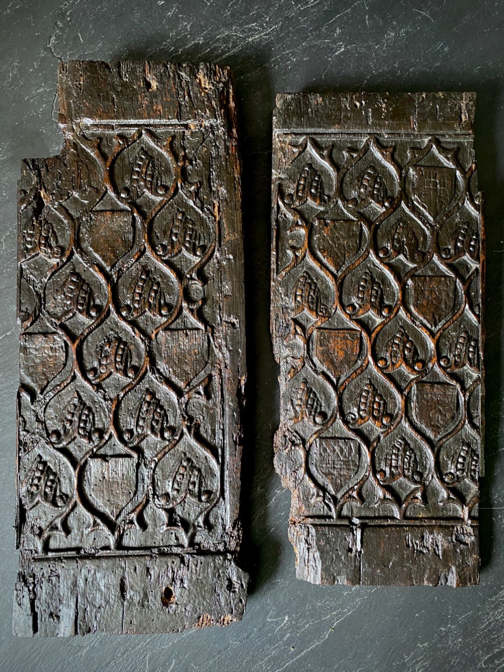 A carved dark oak panel featuring a repetitive geometric foliage pattern beside a detailed close-up of incised concentric circles and ritual marks on the wood grain. View XIII