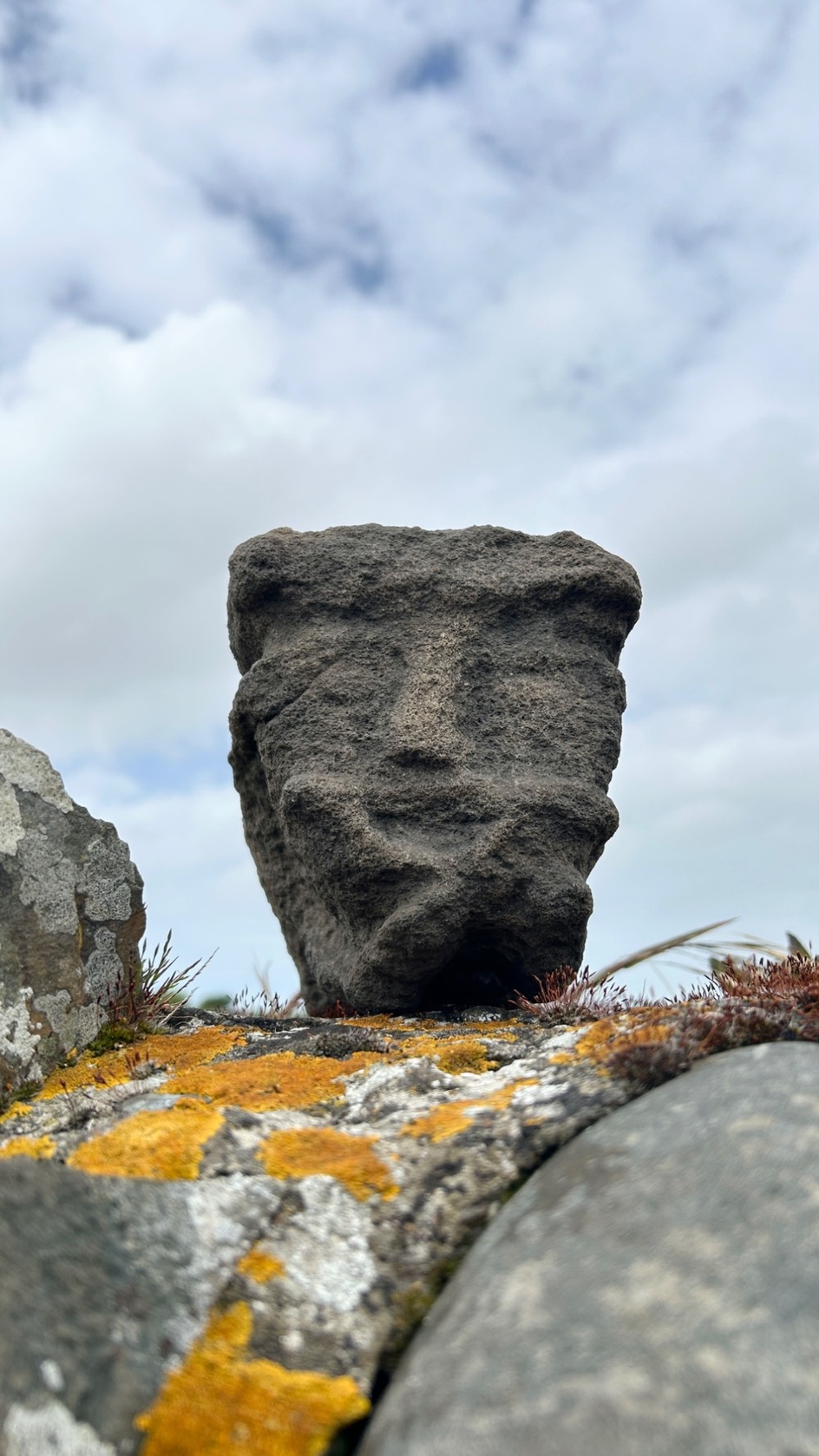 A hand-carved medieval grey stone corbel featuring a stylised human face with a gripping mouth detail.