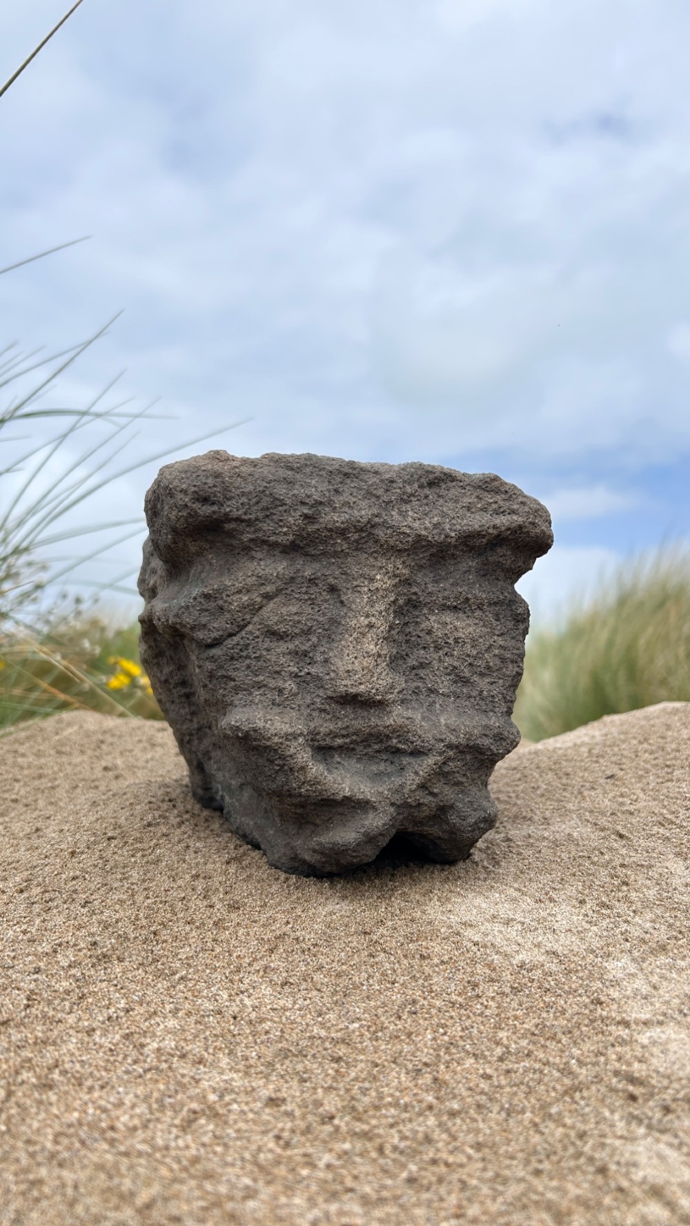 A hand-carved medieval grey stone corbel featuring a stylised human face with a gripping mouth detail. View VIII
