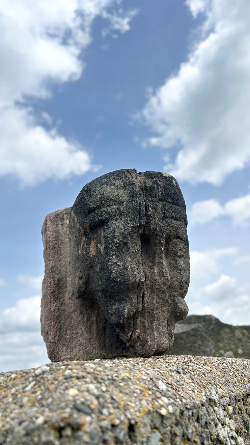 A weathered 17th-century carved stone head fragment with defined facial features and visible surface erosion.
