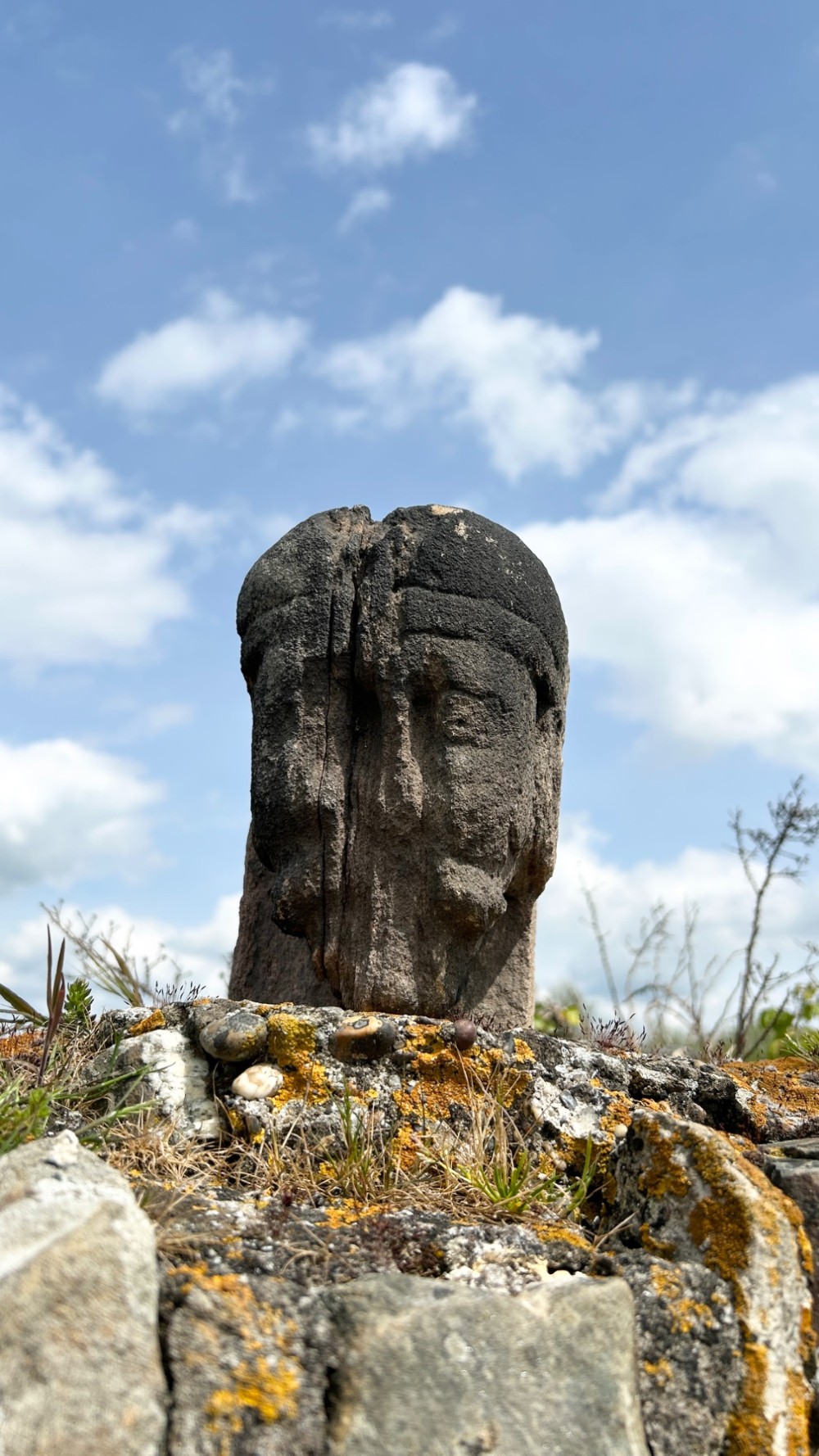 A weathered 17th-century carved stone head fragment with defined facial features and visible surface erosion. View VI